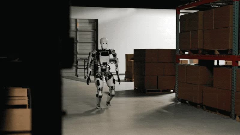Apollo humanoid robot walking past pallet racking