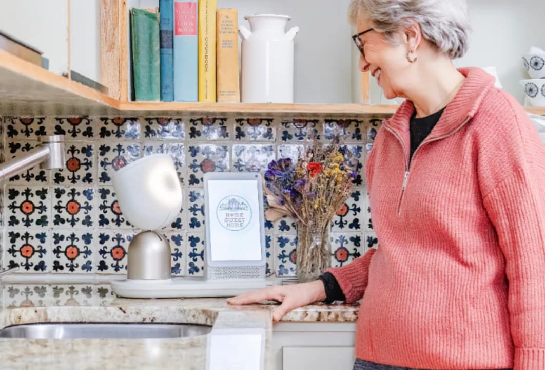 An older woman in a kitchen with ElliQ