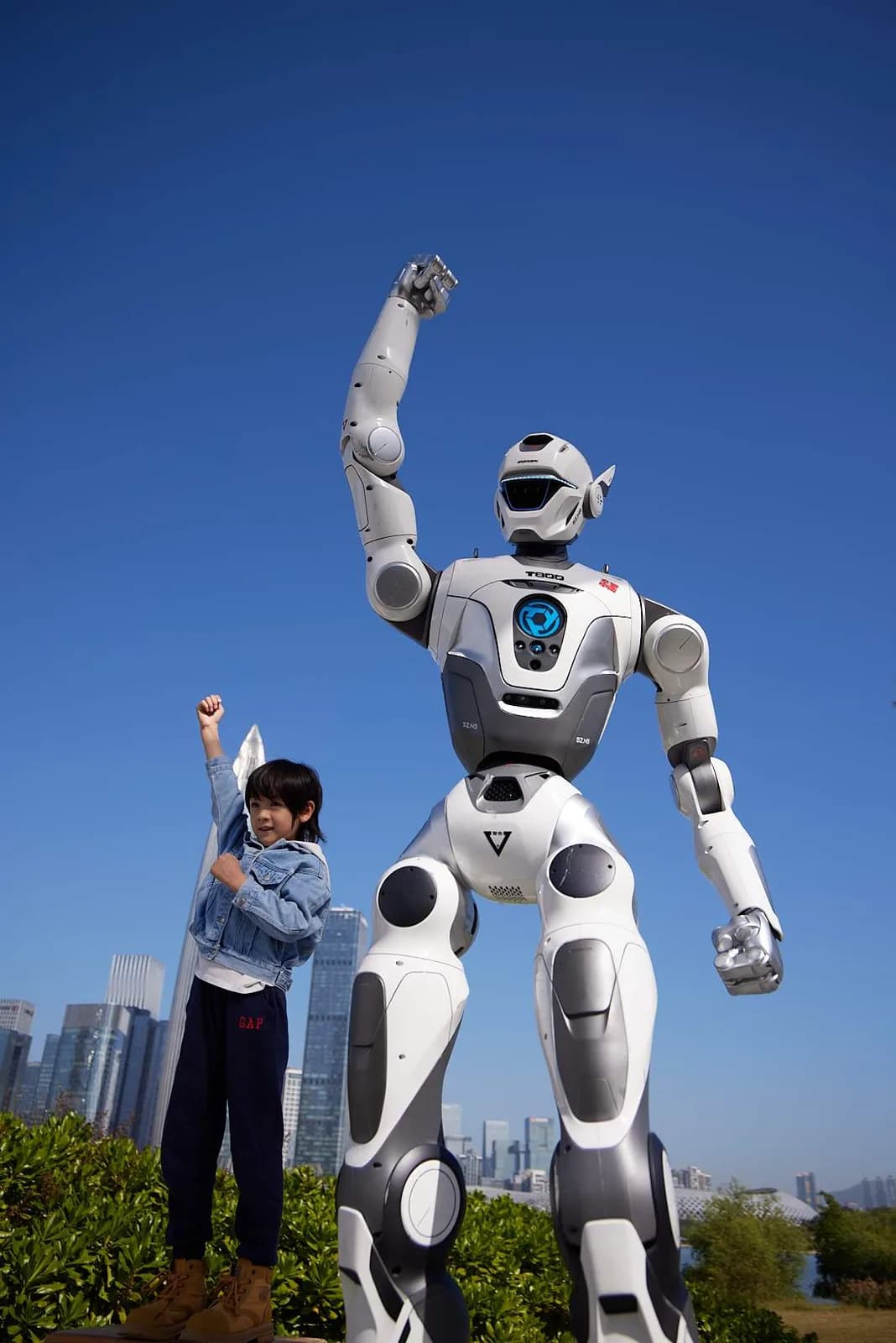 A child raises a fist beside the EngineAI PM01 humanoid robot