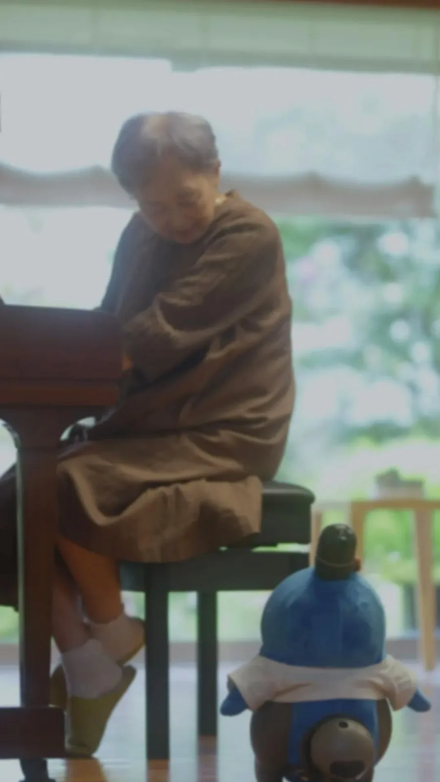 An older person sitting with a LOVOT at home