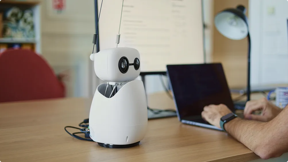 Reachy Mini desktop robot beside a laptop on a desk